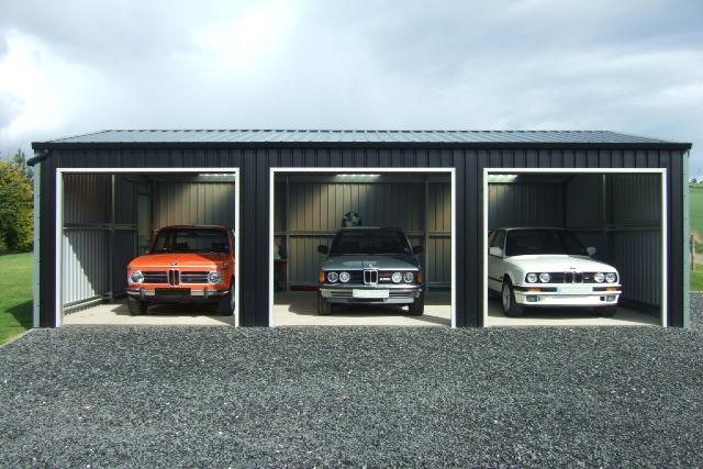Three luxury old cars inside three bays of a building