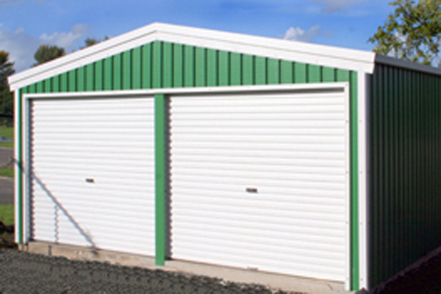 A green farm building with two white roller doors