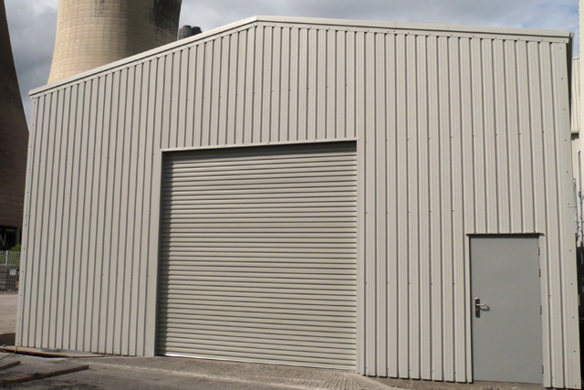 A large grey building with a roller door and personal access door at the front